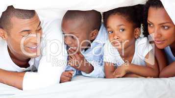 Cheerful family having fun lying down on bed