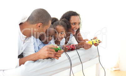 Lively family playing video game lying down on bed