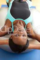 Charming woman doing sit-ups with a pilates ball