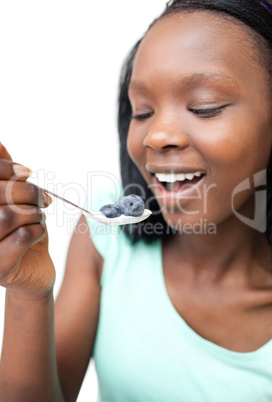 Afro-american woman eating a yogurt with blueberries
