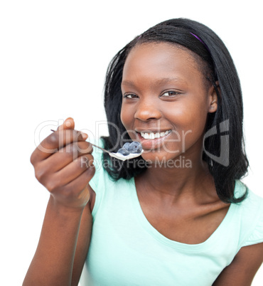 Smiling woman eating a yogurt with blueberries