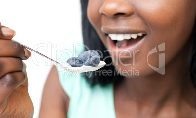 Close-up of a woman eating a yogurt with blueberries