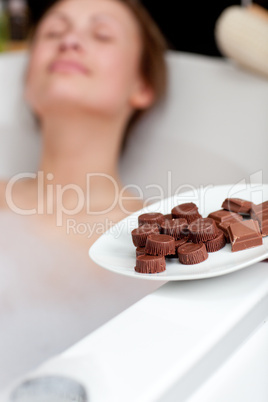 Attractive woman eating chocolate while having a bath