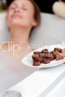 Attractive woman eating chocolate while having a bath