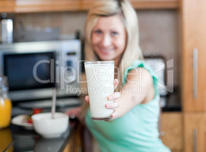 Happy woman holding a glass of milk while having an healthy brea