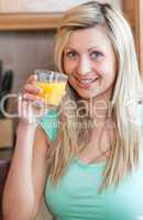 Enthusiastic woman drinking orange juice in a kitchen