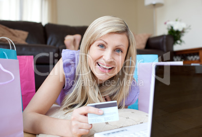 Laughing woman shopping online lying on the floor