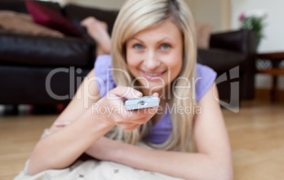 Cheerful woman watching TV lying on the floor