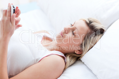 Concentrated woman sending a text lying on a bed