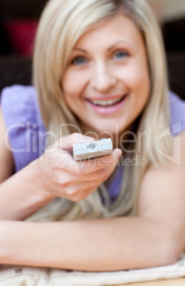 Happy woman watching TV lying on the floor