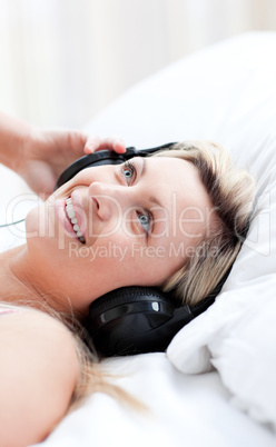 Charming woman with headphones on lying on a bed