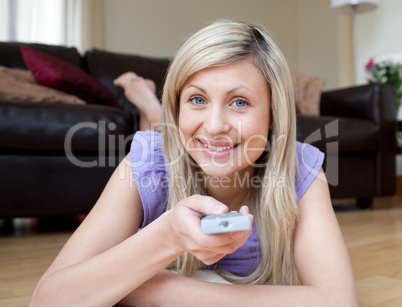 Jolly woman watching TV lying on the floor