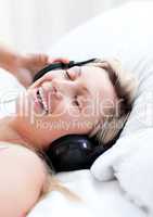 Enthusiastic woman with headphones on lying on a bed