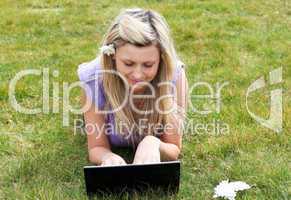 Charming young woman using a laptop in a park