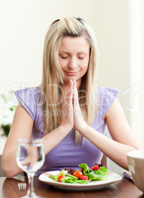 Young woman saying grace before dinner