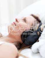 Smiling woman with headphones on lying on a bed