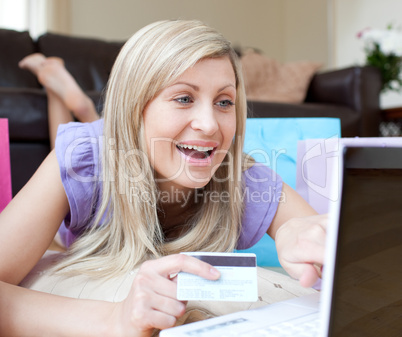Happy woman shopping online lying on the floor