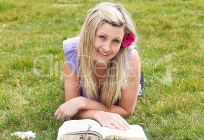 Smiling woman reading a book in a park