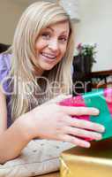 Happy attractive woman holding presents lying on the floor