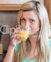 Charming woman drinking orange juice  in a kitchen