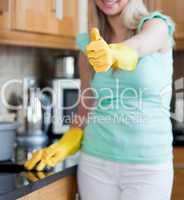Smiling woman with thumb up cleaning a kitchen