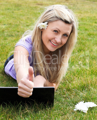Happy young woman using a laptop in a park