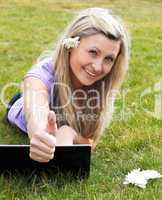 Happy young woman using a laptop in a park