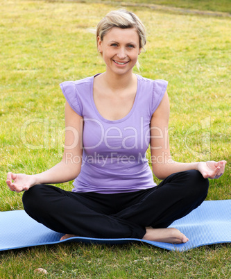 Smiling woman meditating sitting on the grass