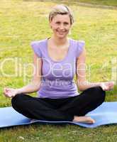 Smiling woman meditating sitting on the grass