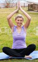 Jolly woman doing yoga sitting on the grass