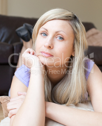 Portrait of a bored blond woman lying on the floor