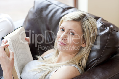 Charming woman reading a book sitting on a sofa
