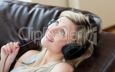 Joyful woman with headphones on lying on a sofa