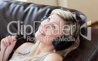 Joyful woman with headphones on lying on a sofa