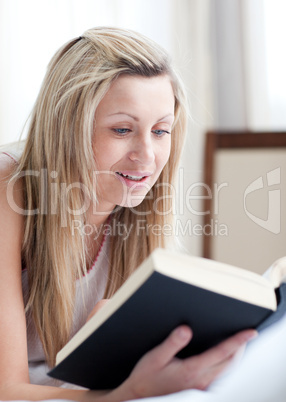 Charming woman reading a book lying on her bed