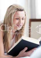 Charming woman reading a book lying on her bed