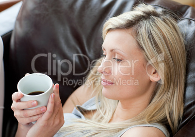 Relaxed woman drinking coffee sitting on a sofa