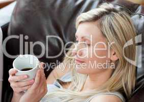 Relaxed woman drinking coffee sitting on a sofa