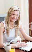 Charming woman using a laptop while having a breakfast