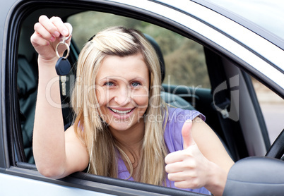Charming female driver showing a key after bying a new car