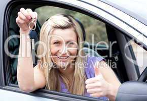 Charming female driver showing a key after bying a new car