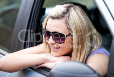 Charming female driver wearing sunglasses in her car