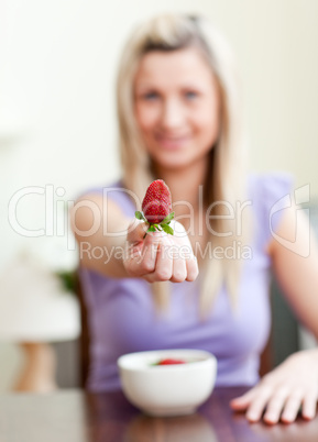 Portrait of a woman showing a strawberry