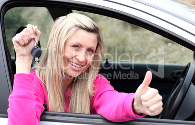 Jolly female driver showing a key after bying a new car