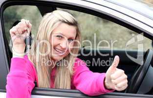 Jolly female driver showing a key after bying a new car