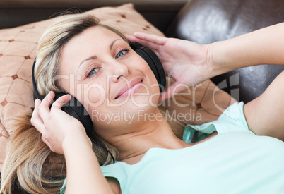 Smiling woman with headphones on lying on a sofa