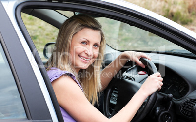 Happy female driver at the wheel sitting in her car