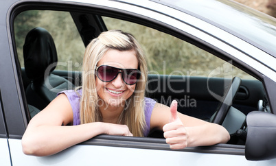 Happy female driver wearing sunglasses with thumb up