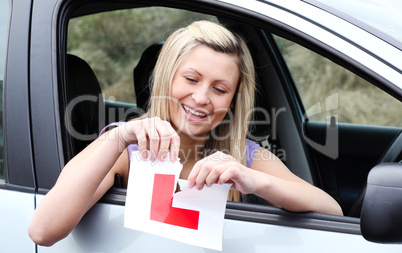 Happy young female driver tearing up her L sign