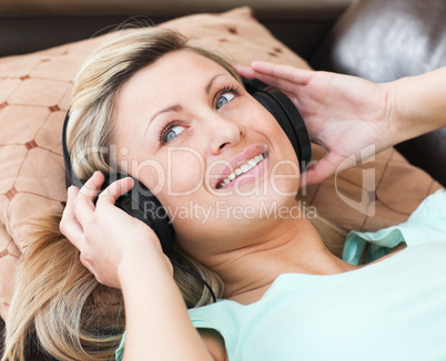 Jolly woman with headphones on lying on a sofa